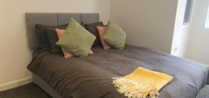 Una cama gris con almohadas y una manta amarilla. en Leicester Central Apartments, en Leicester