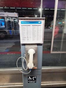 un parchimetro con un telefono di fronte a una finestra di The Atrium Hotel a San Bruno