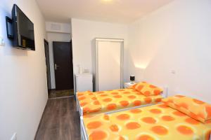 a bedroom with two beds with orange sheets and a flat screen tv at Studio In in Dubrovnik