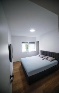 a white bedroom with a bed and a television at Apartman Teo in Velika Gorica
