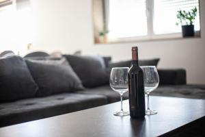 een fles wijn zittend op een tafel met twee wijnglazen bij Apartman Teo in Velika Gorica