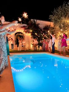 un groupe de personnes debout autour d'une piscine la nuit dans l'établissement Masseria Narducci, à Montalbano