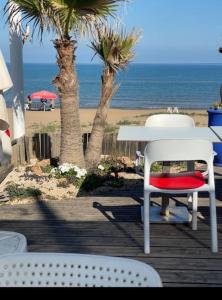 - une table et des chaises sur une terrasse en bois donnant sur la plage dans l'établissement Maison de plage familles, à Saïdia
