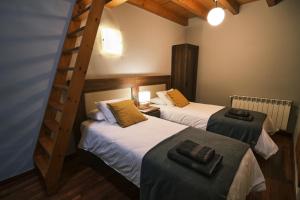 two twin beds in a room with a ladder at Can Mateu, bonito apartamento céntrico con parking in Camprodon