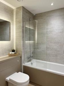 uma casa de banho com uma banheira, um WC e um chuveiro em No29, Luxury Apartment near Bicester Village em Bicester