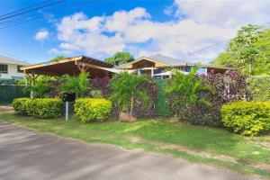 a house with a fence and some bushes at Charming Country Cottage on quiet street just a few steps from the beach! in Waianae