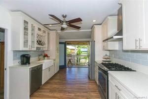a kitchen with white cabinets and a ceiling fan at Charming Country Cottage on quiet street just a few steps from the beach! in Waianae