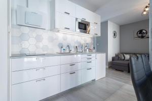 a white kitchen with a sink and a couch at Apartament Old Town Tartaczna 43 in Gdańsk