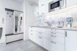a white kitchen with a sink and a microwave at Apartament Old Town Tartaczna 43 in Gdańsk