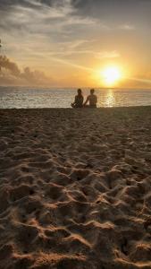 dwoje ludzi siedzących na plaży obserwujących zachód słońca w obiekcie 3B Beach Resort Alegria w mieście Santa Monica