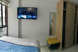 ein Schlafzimmer mit einem Bett und einem TV an der Wand in der Unterkunft Cómodo Apartamento en Bogotá, Chapinero Central - Theatron in Bogotá