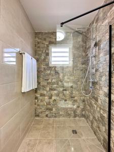 a bathroom with a shower with a stone wall at Lirmar Apartments in Kralendijk