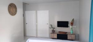 a white bedroom with a tv on a wall at Fare Onavai in Punaauia