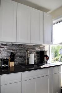 uma cozinha com armários brancos e um balcão preto em LUXE Private & Modern Close to New York City em New Rochelle