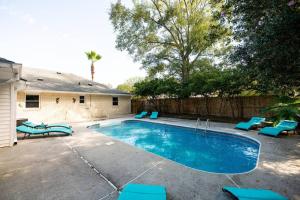 a swimming pool with blue chairs next to a house at Relaxing 5-Bedroom Villa with Outdoor Oasis in Bay Saint Louis