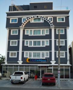 un grand bâtiment bleu avec des voitures garées dans un parking dans l'établissement City Caribbean Hotel Boutique, à Saint-Domingue