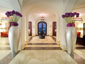 Deux vases blancs avec des fleurs violettes dans un couloir dans l'établissement Canal House Suites at Sofitel Legend The Grand Amsterdam, à Amsterdam