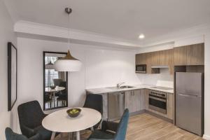 uma cozinha com mesa e cadeiras e uma cozinha com lavatório em Adina Apartment Hotel Coogee Sydney em Sydney