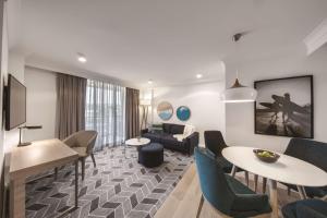 een woonkamer met een bank en tafels en stoelen bij Adina Apartment Hotel Coogee Sydney in Sydney