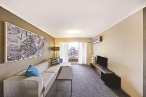 a living room with a couch and a tv at Adina Apartment Hotel Sydney Surry Hills in Sydney