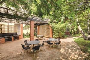 un patio con mesas, sillas y un piano en Adina Apartment Hotel Sydney Surry Hills, en Sídney