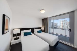 two beds in a hotel room with a large window at Adina Apartment Hotel Wollongong in Wollongong +25 photos
