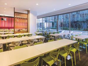 um restaurante com mesas, cadeiras e janelas em Travelodge Hotel Melbourne Docklands em Melbourne