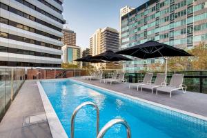 a pool with chairs and umbrellas on a building at Vibe Hotel North Sydney in Sydney