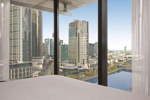 メルボルンにあるVibe Hotel Melbourneの市街のスカイラインを望むベッドルーム1室
