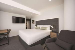Habitación de hotel con cama, escritorio y silla en Vibe Hotel Melbourne en Melbourne