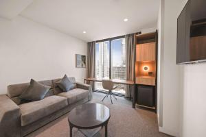 a living room with a couch and a table at Vibe Hotel Melbourne in Melbourne