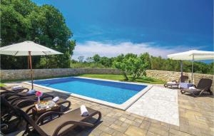 a swimming pool with two umbrellas and chairs and a table at Lovely Home In Turcic With Kitchen in Vantačići