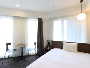 a hotel room with a bed and a table and chairs at HOTEL M's EST KYOTO STATION SOUTH in Kyoto