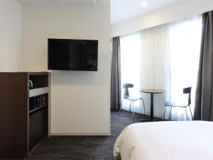 a hotel room with a bed and a flat screen tv at HOTEL M's EST KYOTO STATION SOUTH in Kyoto