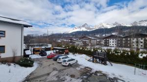 een groep auto's geparkeerd op een parkeerplaats met sneeuw bedekte bergen bij Appartement Franco in Maria Alm am Steinernen Meer