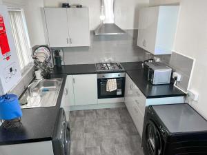 a small kitchen with a sink and a microwave at Adorable 2 bed house ideal for Family of Four in Manchester