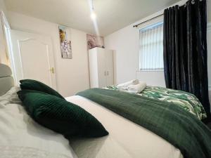 1 dormitorio con 1 cama grande con almohadas verdes en Adorable 2 bed house ideal for Family of Four, en Mánchester