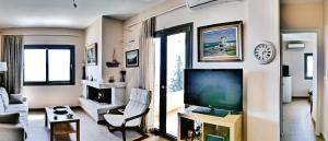 a living room with a flat screen tv and a couch at Cozy Sunset House in Aegina Town