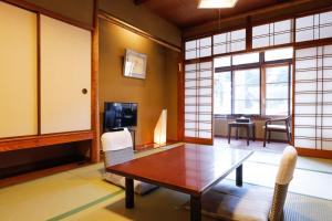 a living room with a table and chairs and a television at Tsuruya Ryokan in Toyooka +22 photos