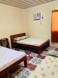 a room with three beds in it with a fan at Jeremias Transient Patar Bolinao near WhiteBeach LightHouse in Bolinao
