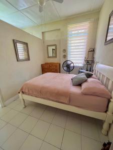 a bedroom with a bed with pink sheets and a window at Cozy 1 bedroom cottage w/pool in Bridgetown