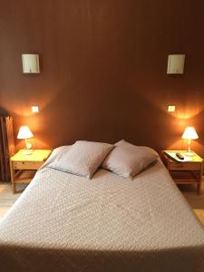 ein Schlafzimmer mit einem großen Bett mit zwei Lampen an zwei Tischen in der Unterkunft Le Commerce in La Haye-du-Puits