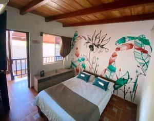 1 dormitorio con 1 cama con una pintura en la pared en Kayena Hostel, en Santa Marta