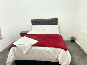 a bedroom with a large bed with a red blanket at Lovely 3 Bed Apartment Near QE Hospital Harborne Birmingham New in Birmingham