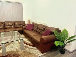 a brown leather couch in a living room with a glass table at Lovely 3 Bed Apartment Near QE Hospital Harborne Birmingham New in Birmingham