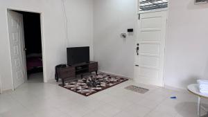 Cette chambre blanche dispose d'une télévision et d'une porte. dans l'établissement Homestay Mama, Kota Bharu, à Kota Bharu