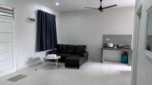 - un salon avec un canapé noir et une table dans l'établissement Homestay Mama, Kota Bharu, à Kota Bharu
