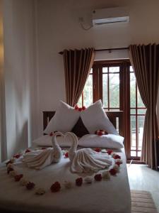 two swans sitting on a bed with flowers on it at White House Family Stay in Maspota +66 photos