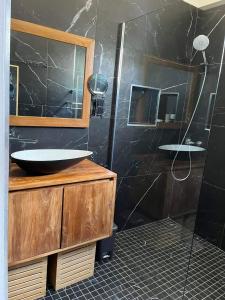 La salle de bains est pourvue d'un lavabo et d'une douche en verre. dans l'établissement Le Pavillon du trou d'eau, à La Saline les Bains