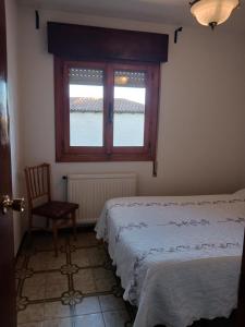 a bedroom with a bed and a window and a chair at La Casita de Cabanillas. Cabanillas de la Sierra. in Cabanillas de la Sierra